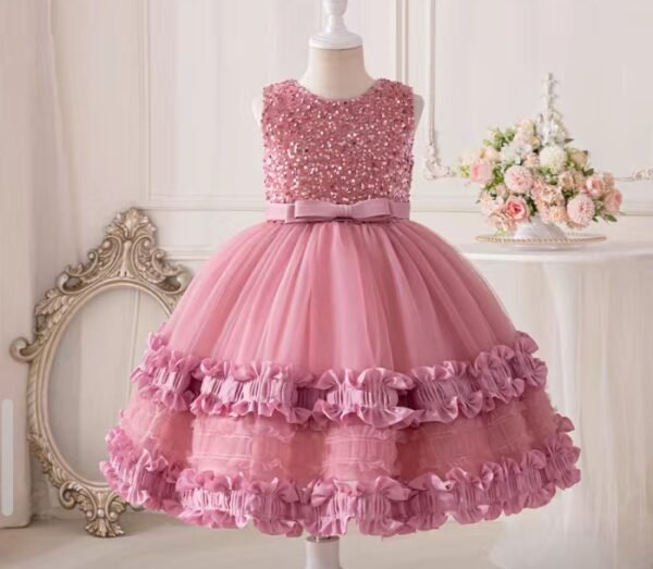 Cette robe est un joli modèle de fête pour enfant, de couleur rose tendre